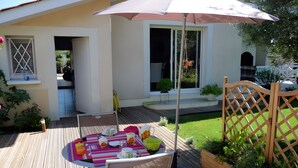 Un patio con una mesa lista para comer, una silla y una cerca de madera.