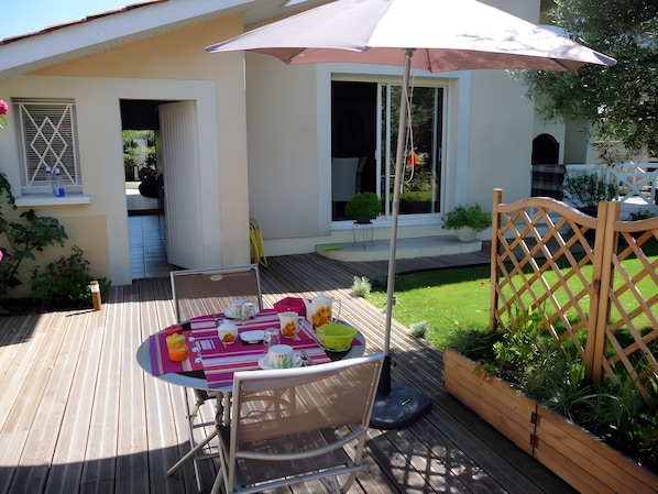 Un patio con una mesa lista para comer, una silla y una cerca de madera.