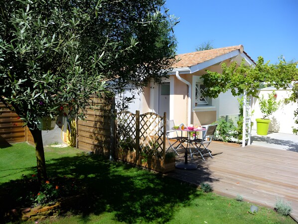 A house with a patio, a wooden deck, and a garden.