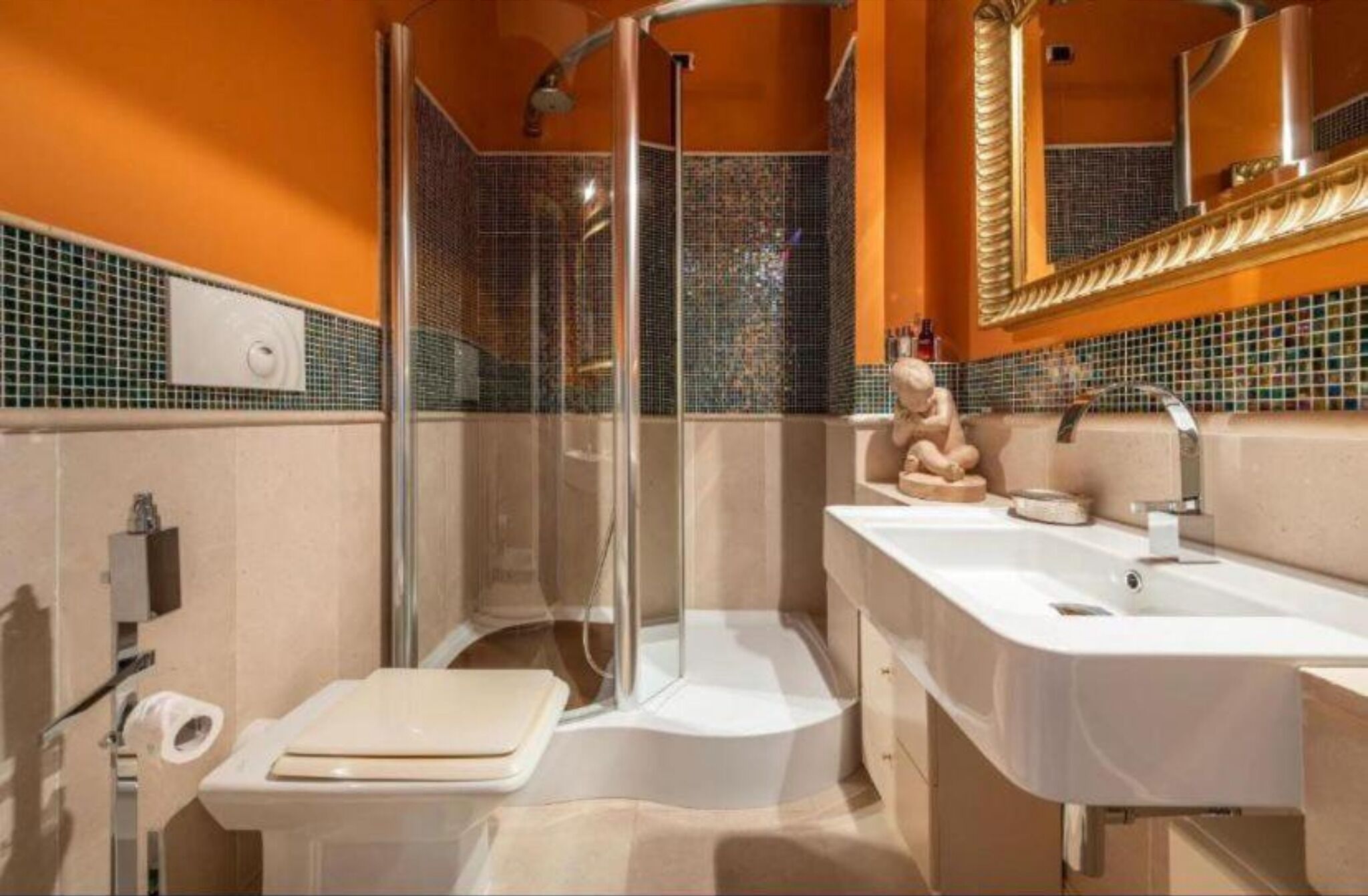 Een moderne badkamer met een douchecabine van glas, een witte wastafel en een toilet.
