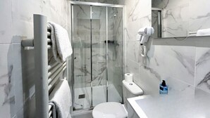 Een moderne badkamer met een douchecabine van glas, een toilet en een wastafel met een marmeren aanrechtblad.