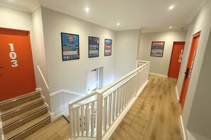 A hotel hallway with a staircase, white walls, and red doors numbered 103 and 106. - never@home Hermanus (Hermanus)