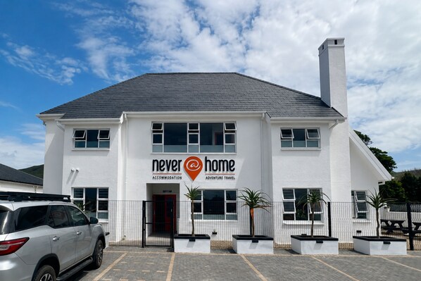 A two-story building with a sign reading 'Never at Home Accommodation & Adventure Travel'.