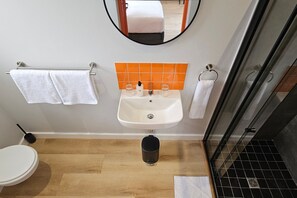 A bathroom with a white sink, a mirror above it, and a toilet. - never@home Hermanus (Hermanus)