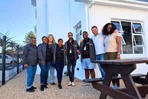 A group of people standing outside a building with a white exterior and a gravel ground. - never@home Hermanus (Hermanus)