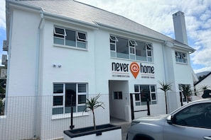 A white building with a sign reading 'Never Home Accommodation Adventure Travel'. - never@home Hermanus (Hermanus)