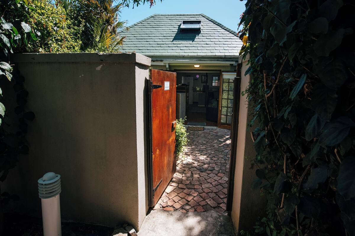 A narrow stone pathway leading to a building with a sloped roof and a small skylight.