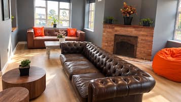A modern living room with a leather sofa, a fireplace, and a large window.