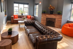 Moderni olohuone, jossa on nahkasohva, takka ja suuri ikkuna.