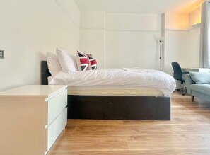 A modern bedroom with a bed, bedside table, and a desk. - Finchley Ground Floor Apartment (London)