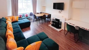 A modern living room with a sectional sofa, a dining table, and a flat-screen TV. - Finchley Ground Floor Apartment (London)