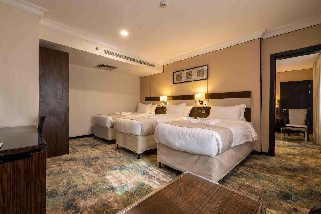 A hotel room with two beds, a desk, and a mirror.