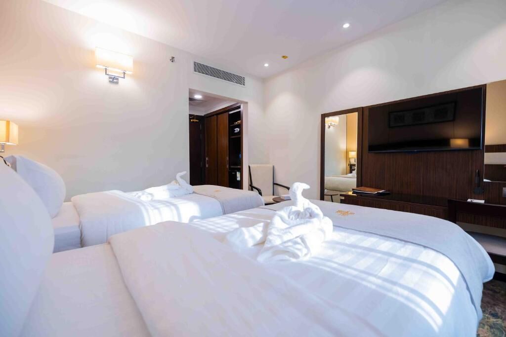 A hotel room with two beds, a TV, a desk, and a wardrobe.