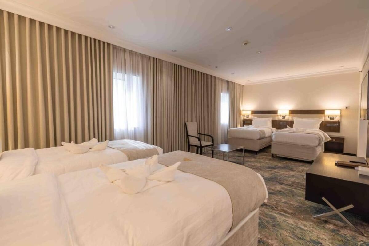 Quarto de hotel com duas camas, uma escrivaninha e uma cadeira.