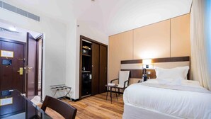 Ein Hotelzimmer mit Bett, Schreibtisch, Stuhl, Kleiderschrank und einem kleinen Tisch.