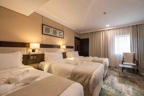 Una habitación de hotel con tres camas, un escritorio y una silla.