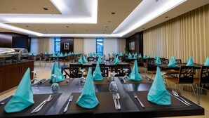 Ein Konferenzraum mit mehreren Tischen, gedeckt für ein Essen, ausgestattet mit Besteck und Gläsern, und einer linken Buffetzeile.