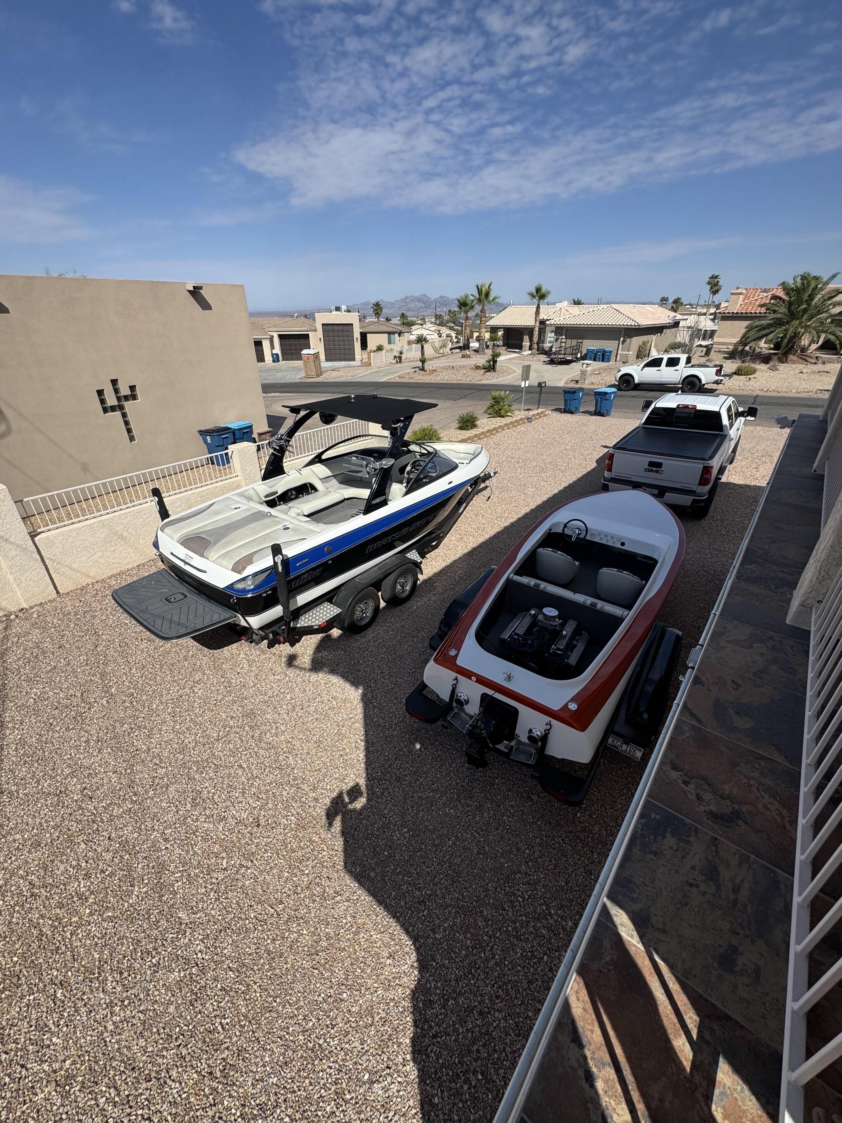 Uma área de estacionamento com um reboque para barco, um barco pequeno e uma caminhonete.