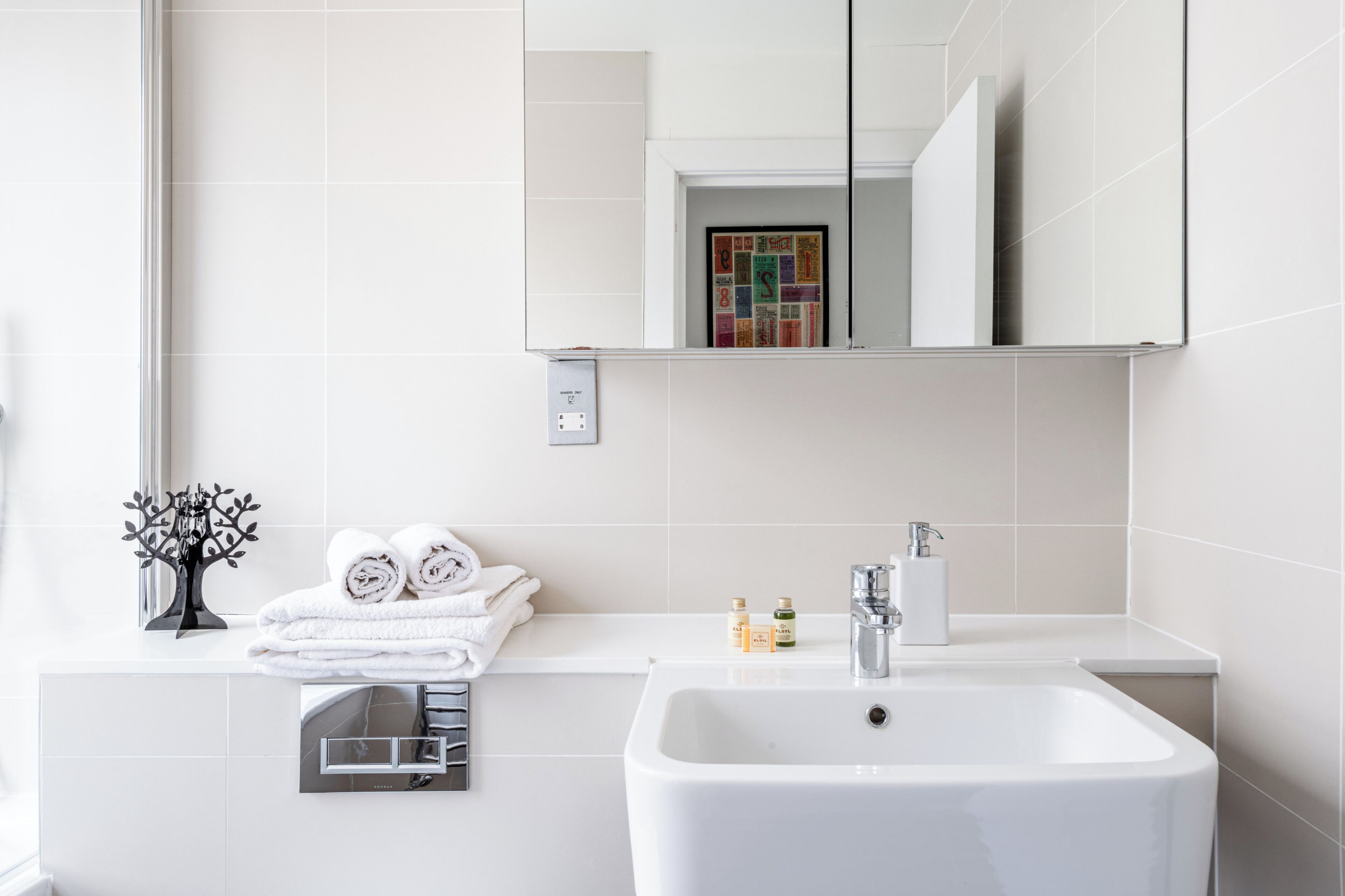 Een moderne badkamer met een witte wasbak, een spiegel en een handdoekhouder.