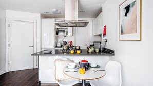 Een moderne keuken met een centraal kookeiland, witte kasten en een magnetron.