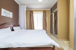 A neatly made bed with white linens in a room with beige walls and a wooden headboard. - Gorgeous 3-bedroom bungalow in tranquil Kitengela perfect for relaxing. (Kitengela)