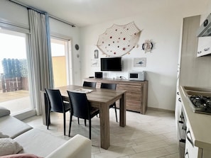 A modern kitchen with a dining area, a TV, and a microwave.