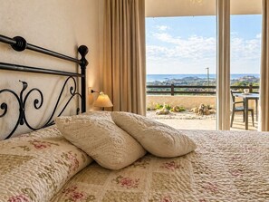 Ein Bett mit einer blumigen Steude, einer Lampe und Blick ins Freie.