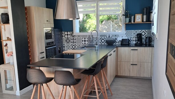 Una cocina moderna con una isla central, taburetes de bar y una mesa de comedor.