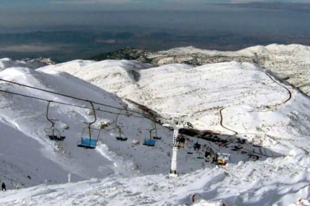 A snow-covered ski slope with a ski lift and chairlift.