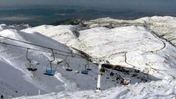 A snow-covered ski slope with a ski lift and chairlift.