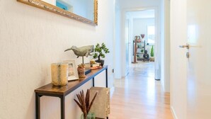 A hallway with a console table, a mirror, and a Buddha statue. - EG R City Wohnung Balkon nähe Salzburg (Freilassing)