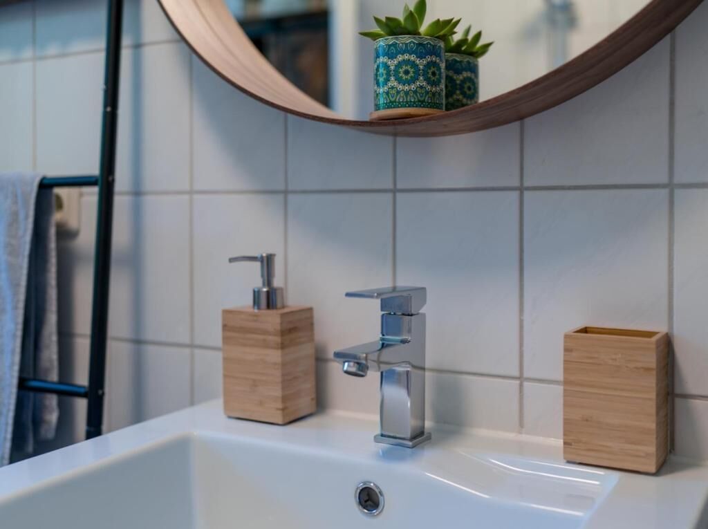 A bathroom with a white sink, two wooden soap dispensers, and a mirror with a wooden frame.