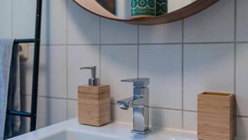 A bathroom with a white sink, two wooden soap dispensers, and a mirror with a wooden frame.
