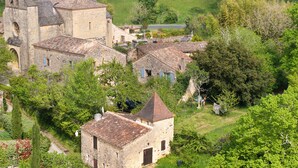 A historic village with stone buildings, including a church with a bell tower, surrounded by lush greenery. - Charming Cottage in Biron (Biron)