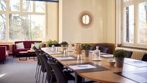 Ein Konferenzraum mit langem Tisch, Stühlen und Topfpflanzen.