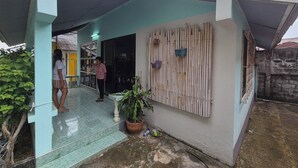 Uma entrada coberta com piso de azulejos, cerca de madeira e um vaso de planta.