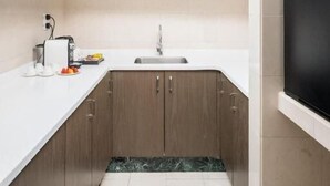 Eine moderne Küche mit Holzausbau, einer weißen Arbeitsplatte, einem schwarzen Kühlschrank und einer gefliesten Spritzschutzwand.