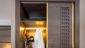 Ein begehbarer Kleiderschrank mit Spiegel, Kleiderhaken und einem Paar Hausschuhen.