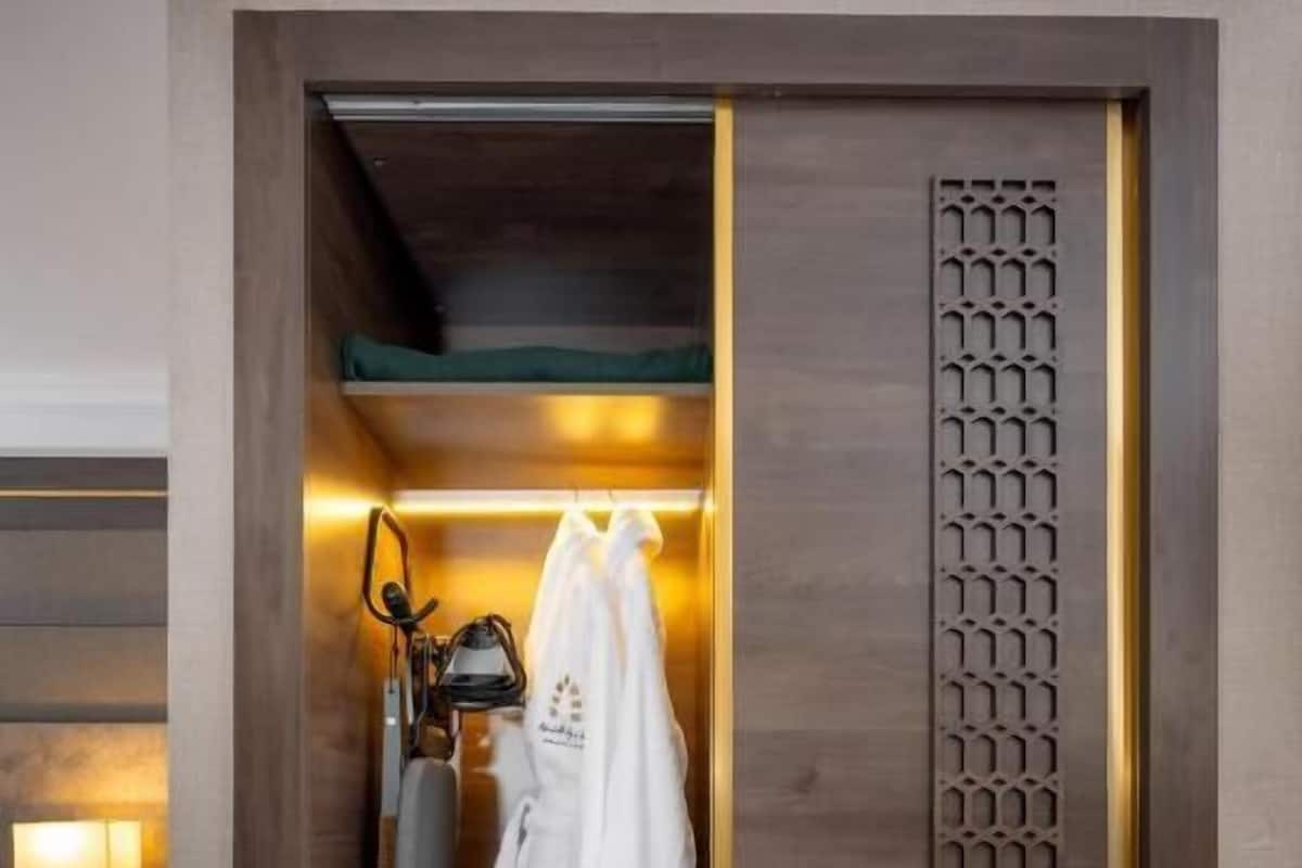 Ein begehbarer Kleiderschrank mit Spiegel, Kleiderhaken und einem Paar Hausschuhen.