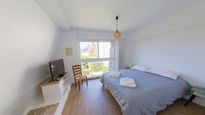 A bedroom with a bed, a TV on a stand, a chair, and a window. - Cosy bed and breakfast downtown Avranches (Avranches)