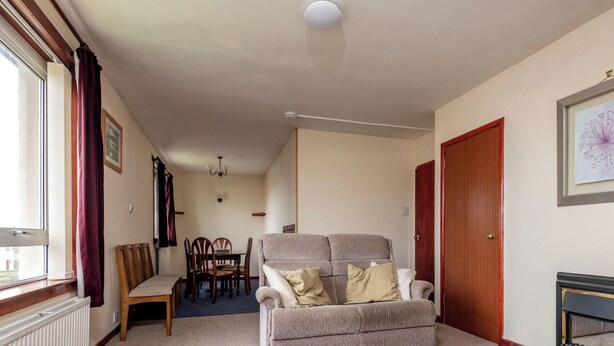 Una sala de estar con sofá, sillas, chimenea, mesa de comedor y candelabro.