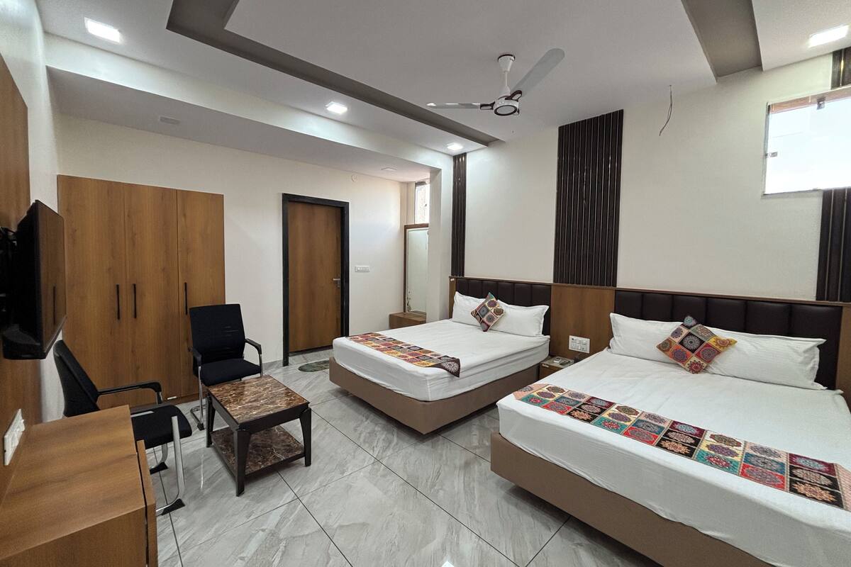 A hotel room with two beds, a desk, a chair, and a wardrobe.