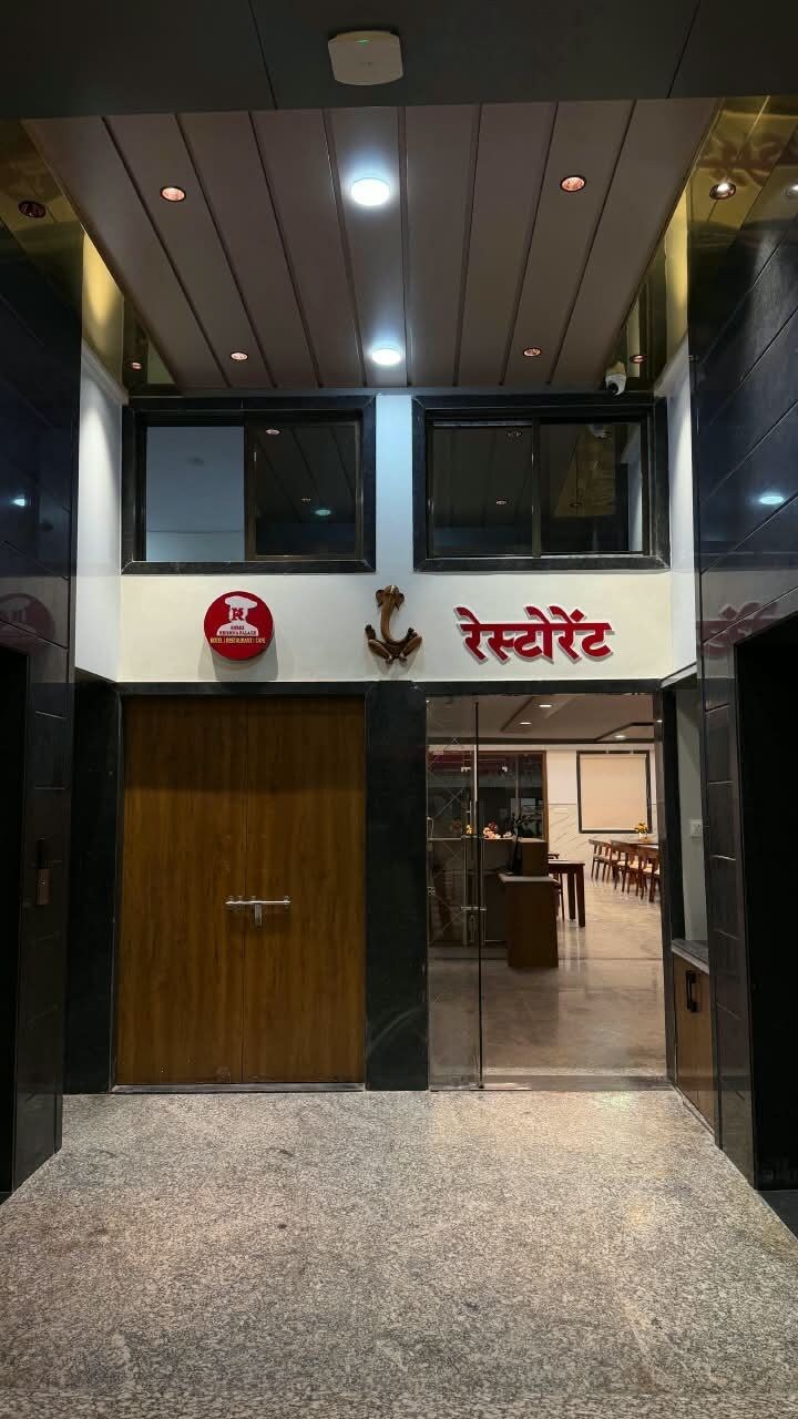 Entrada de hotel con puerta de madera, un mostrador de recepción y un área de estar visible en el interior.