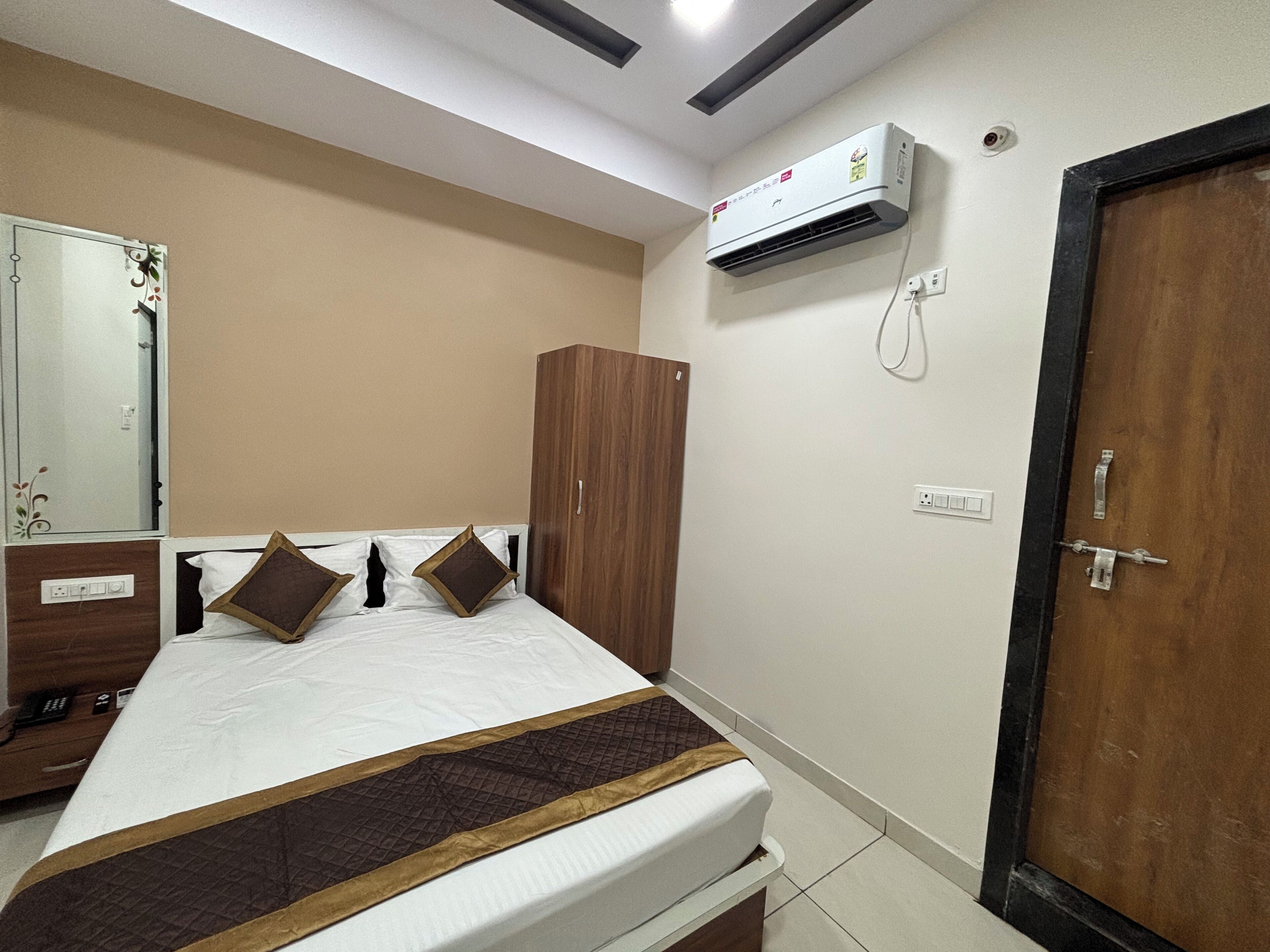 A bedroom with a bed, wardrobe, and an air conditioning unit.