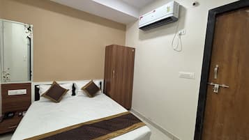 A bedroom with a bed, wardrobe, and an air conditioning unit.