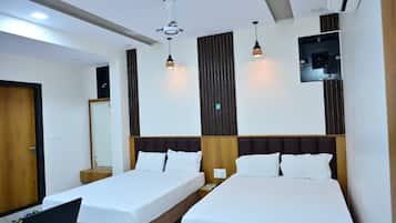 A hotel room with two beds, a ceiling fan, pendant lights, a mirror, and a small table.