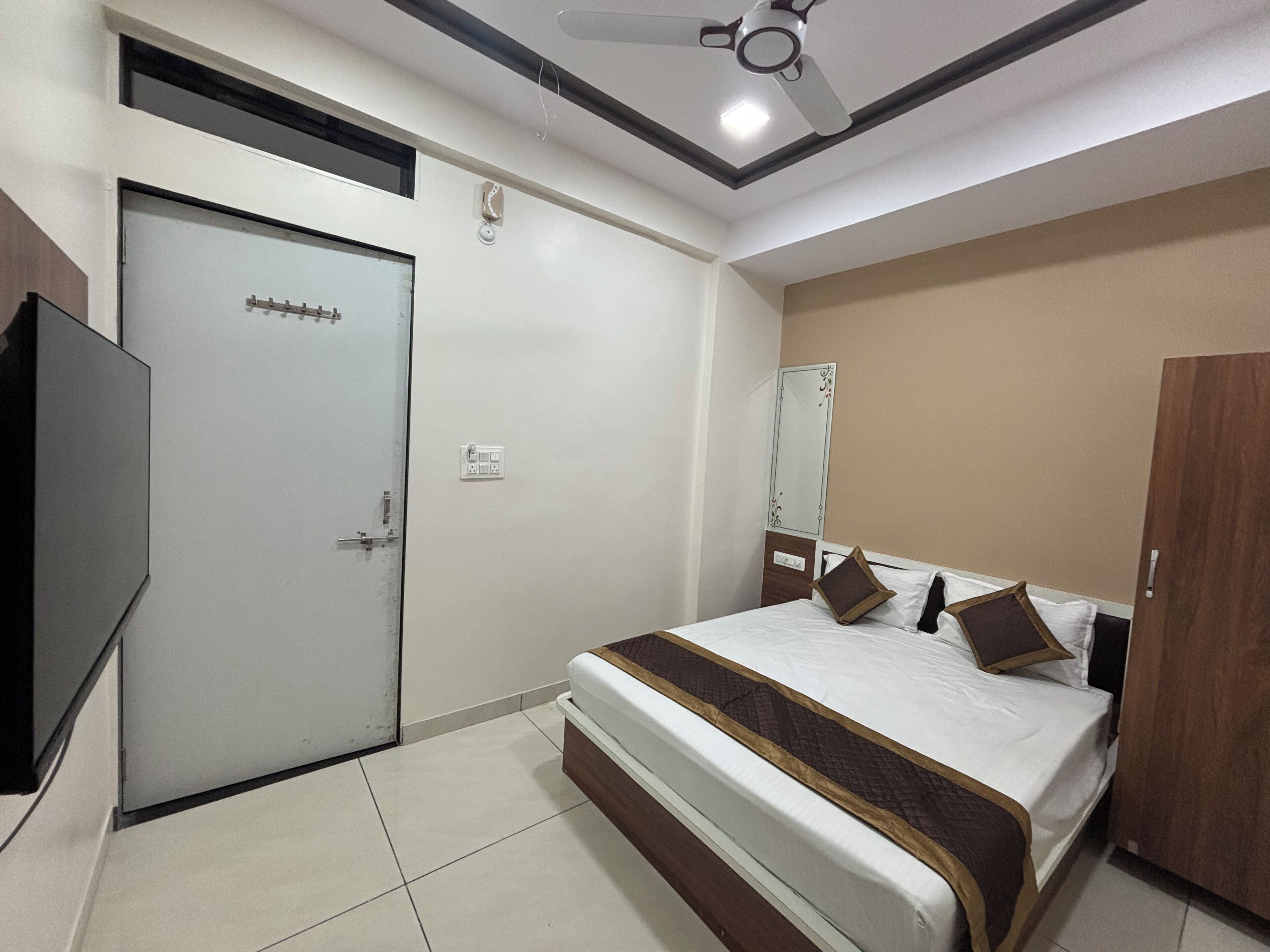 A hotel room with a bed, a wardrobe, a television, and a ceiling fan.