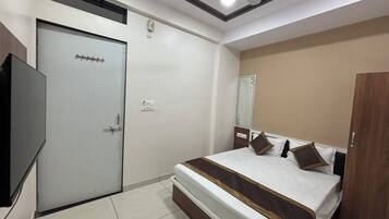 A hotel room with a bed, a wardrobe, a television, and a ceiling fan.