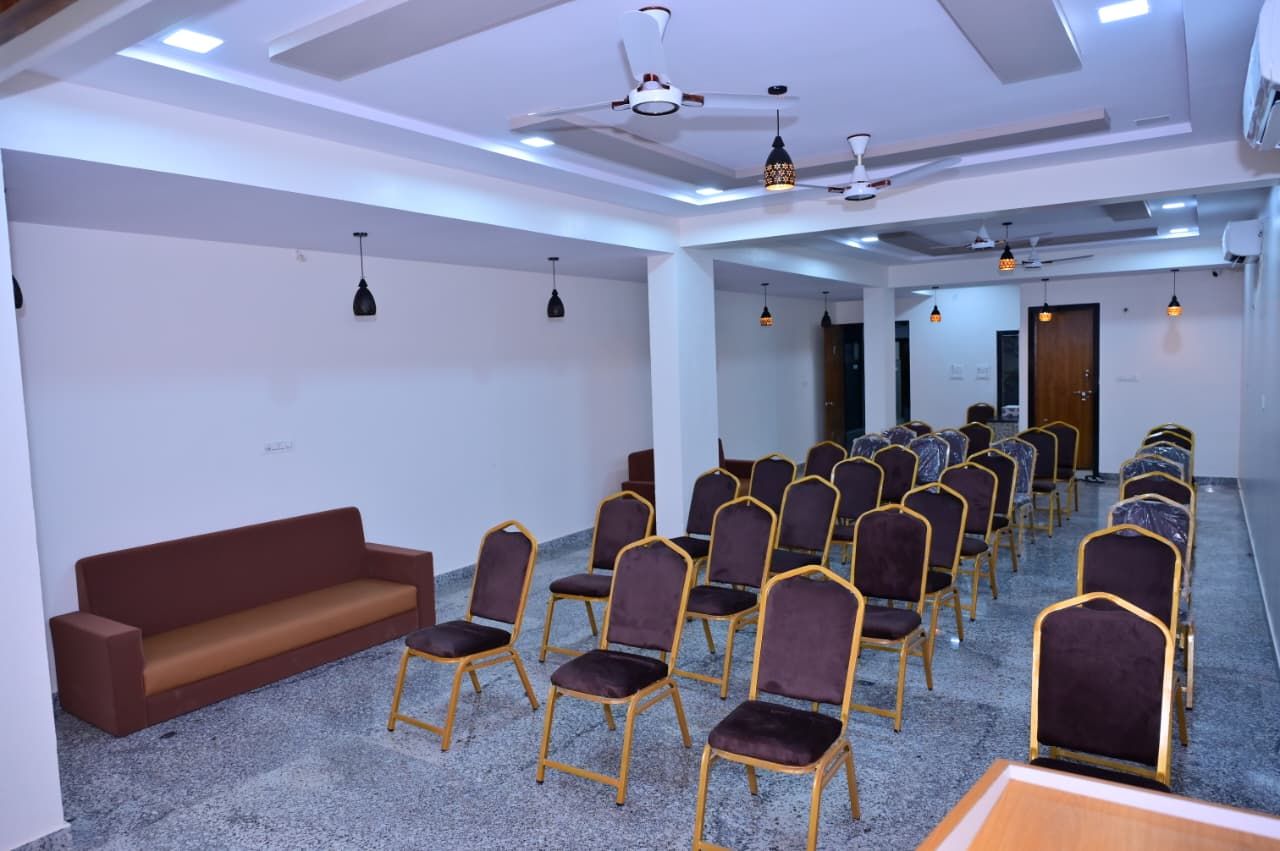 A conference room with rows of chairs, a sofa, and ceiling fans.