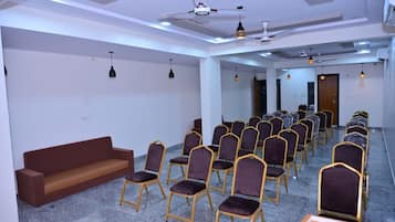 A conference room with rows of chairs, a sofa, and ceiling fans.